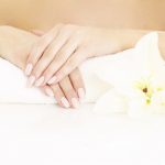 A picture of a young woman showing her hands and manicure over white background